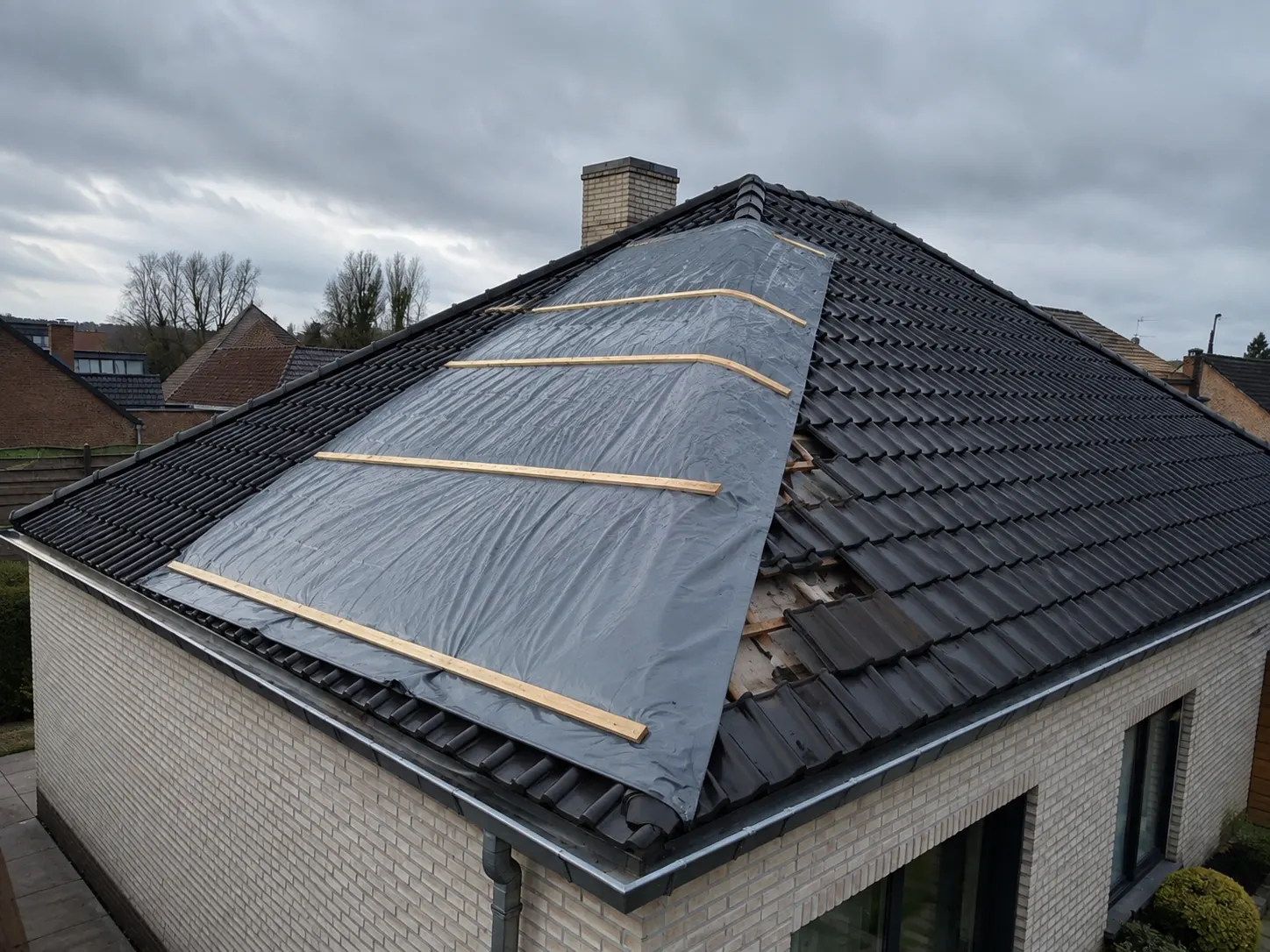 Noodherstelling met waterdicht zeil op een dak na stormschade in Oost-Vlaanderen